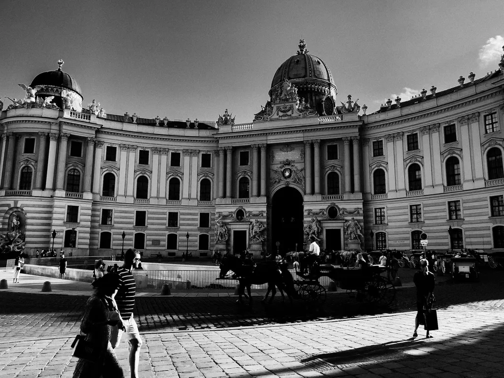 Michaelertrakt der Hofburg mit Fiakern und Passanten im Gegenlicht