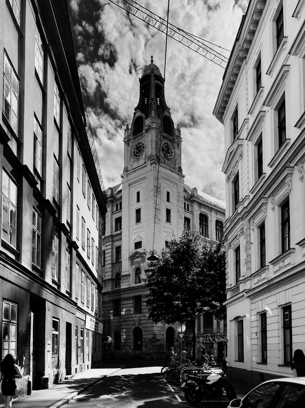 Schmale Gasse mit Altbauten, die auf einen Uhrturm zuläuft
